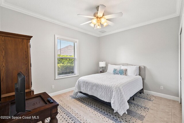 bedroom featuring ceiling fan, a textured ceiling, ornamental molding, and light tile patterned floors