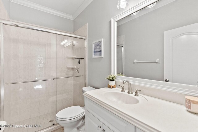 bathroom with toilet, crown molding, vanity, and a shower with door