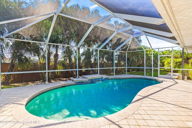 view of pool featuring a hot tub, a patio area, and a lanai