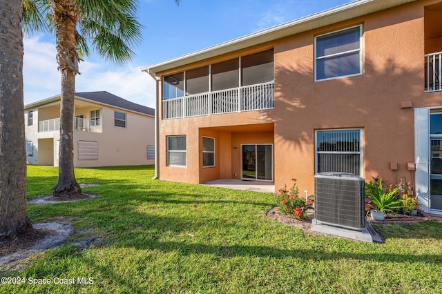 back of property featuring central AC, a sunroom, a lawn, and a balcony