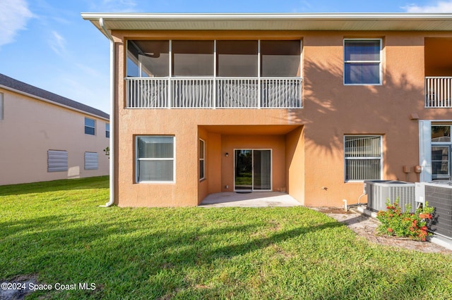 back of house featuring a patio area, a balcony, a lawn, and central AC unit