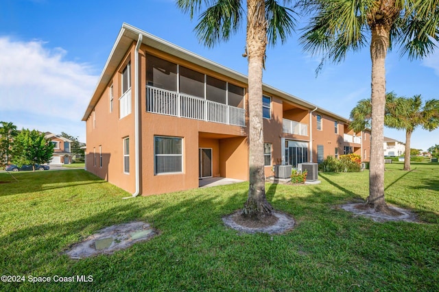 rear view of property featuring central air condition unit, a yard, and a balcony