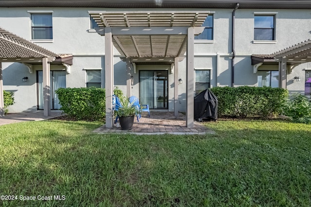 rear view of property with a pergola, a patio, and a lawn