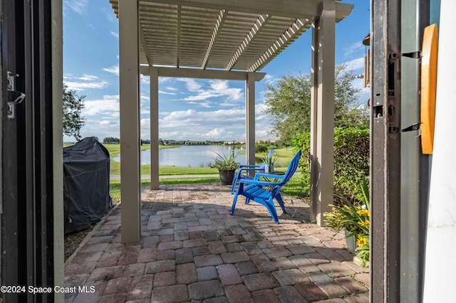 view of patio with a water view, area for grilling, and a pergola