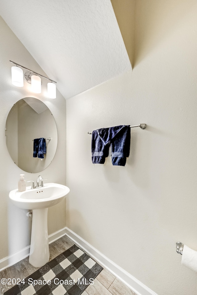 bathroom featuring wood-type flooring and vaulted ceiling