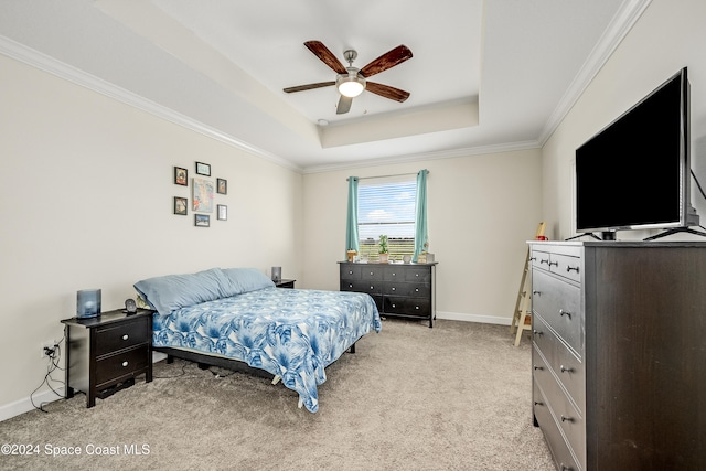 carpeted bedroom featuring ceiling fan, a tray ceiling, and crown molding