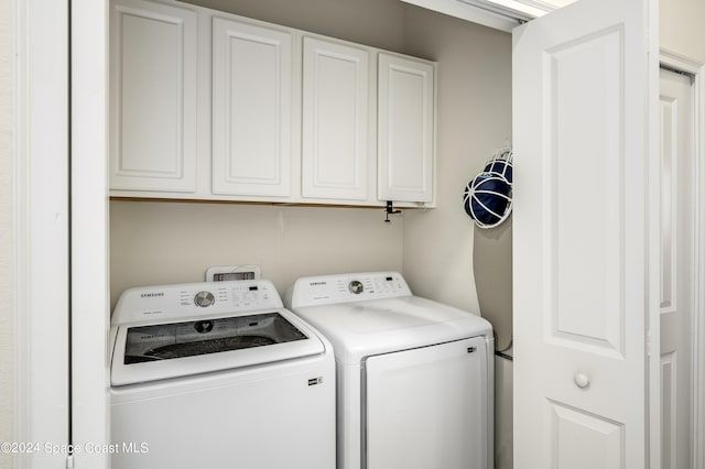 laundry area featuring separate washer and dryer and cabinets