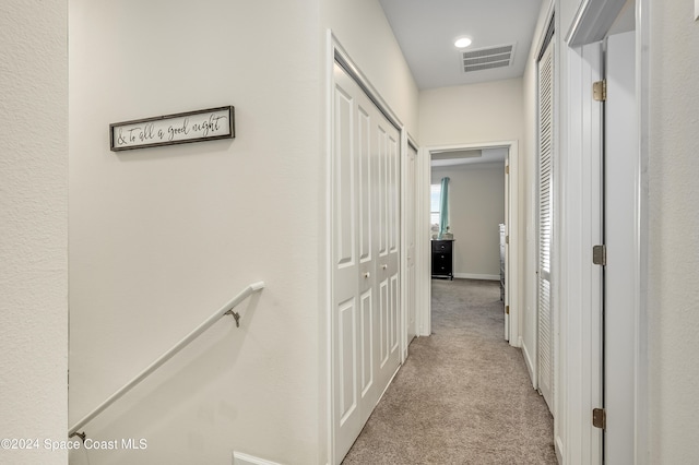 hallway featuring light colored carpet