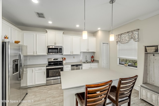 kitchen with light hardwood / wood-style floors, hanging light fixtures, stainless steel appliances, and white cabinets