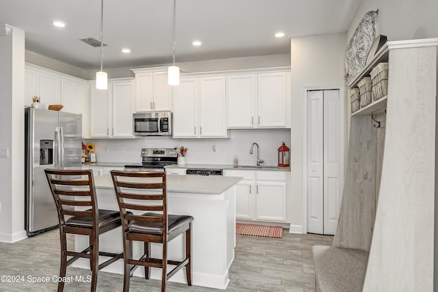 kitchen with stainless steel appliances, white cabinets, and decorative light fixtures