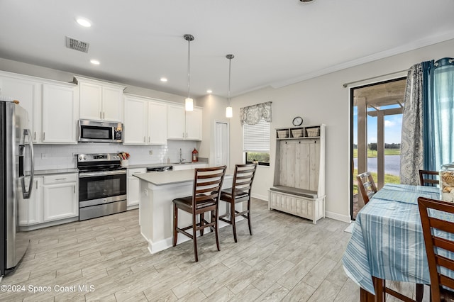 kitchen with pendant lighting, white cabinets, appliances with stainless steel finishes, and a center island