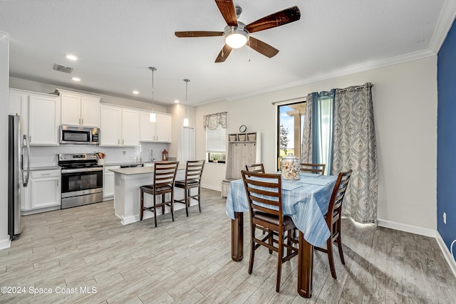 dining space featuring ceiling fan, sink, crown molding, and light hardwood / wood-style floors