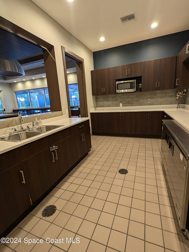 kitchen with dark brown cabinets, light tile patterned floors, sink, and decorative backsplash