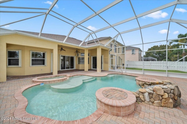 view of swimming pool featuring an in ground hot tub, glass enclosure, ceiling fan, and a patio area