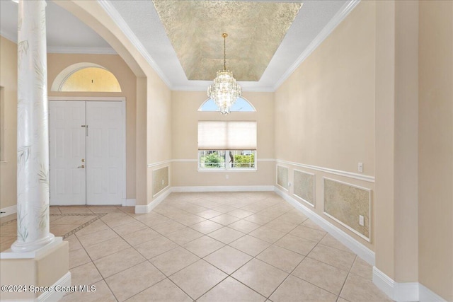 tiled entrance foyer featuring ornamental molding, a tray ceiling, a notable chandelier, and a textured ceiling