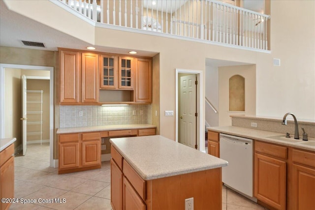 kitchen with a kitchen island, a towering ceiling, sink, dishwasher, and light tile patterned floors