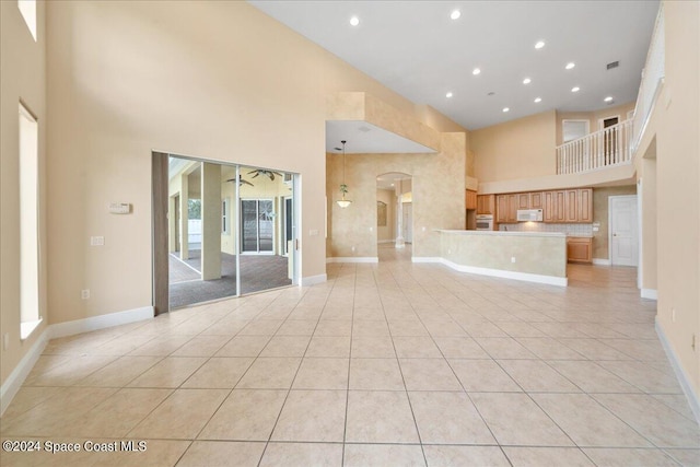 unfurnished living room featuring a towering ceiling and light tile patterned flooring