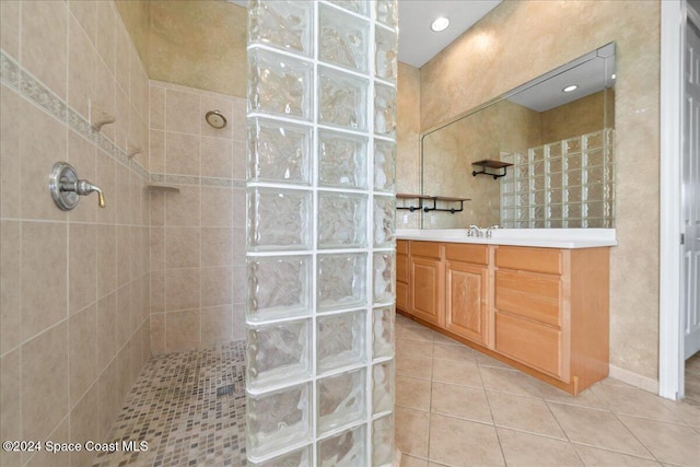 bathroom featuring tile patterned flooring, a tile shower, and vanity