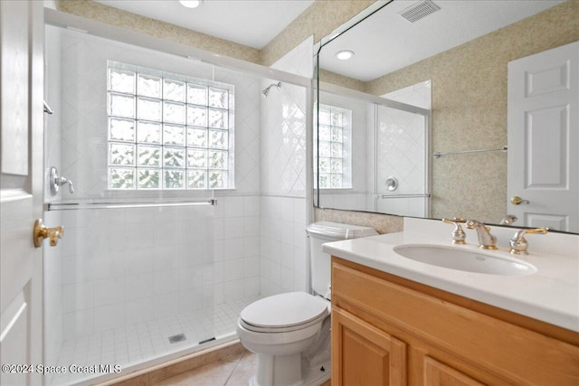 bathroom with vanity, a shower with shower door, toilet, and tile patterned floors