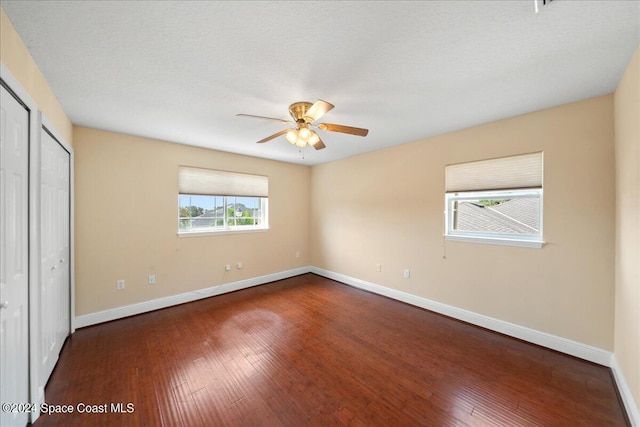 unfurnished bedroom featuring ceiling fan, cooling unit, a textured ceiling, and dark hardwood / wood-style floors