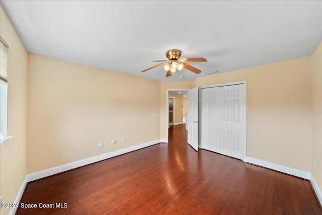 unfurnished bedroom with a closet, dark hardwood / wood-style floors, a textured ceiling, and ceiling fan