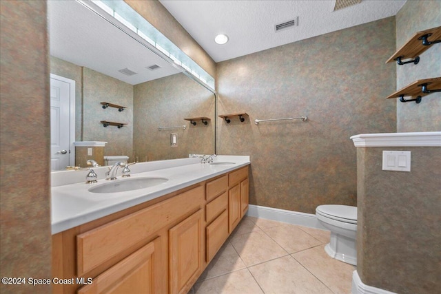 bathroom with vanity, toilet, a textured ceiling, and tile patterned floors