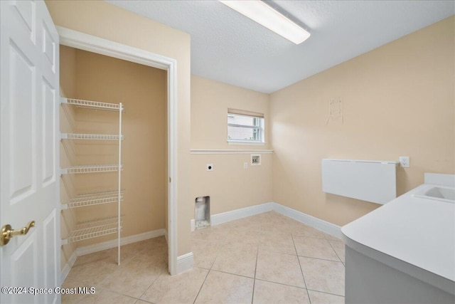 laundry room featuring hookup for a washing machine, hookup for an electric dryer, light tile patterned floors, and a textured ceiling