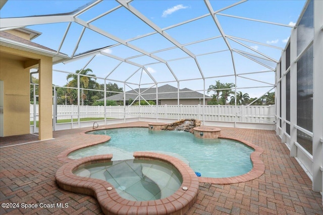 view of swimming pool featuring glass enclosure, an in ground hot tub, and a patio area