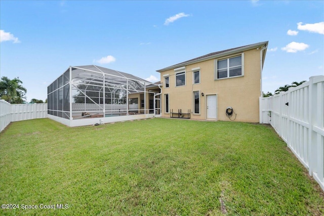 rear view of property with a lanai, a yard, and a patio area