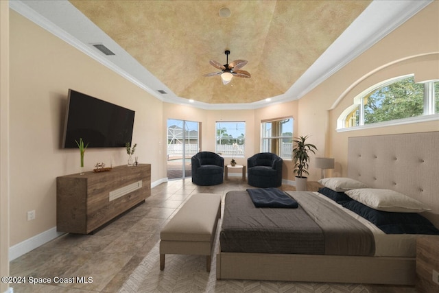 bedroom featuring access to exterior, multiple windows, ceiling fan, and a tray ceiling