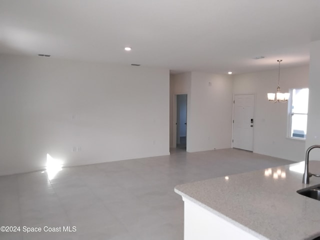 kitchen with pendant lighting, a notable chandelier, a center island with sink, and sink