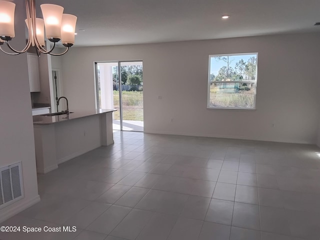 interior space featuring plenty of natural light, light tile patterned floors, sink, and an inviting chandelier