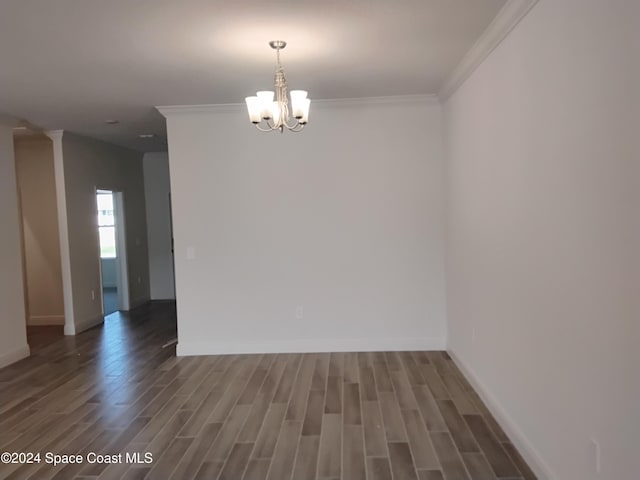 empty room with ornamental molding, dark wood-type flooring, and a notable chandelier