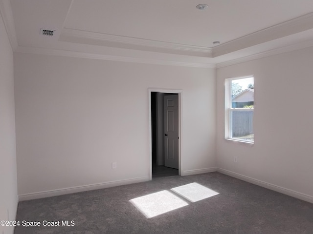 empty room with dark colored carpet, crown molding, and a tray ceiling