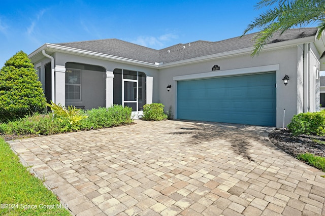 ranch-style home featuring a garage, decorative driveway, a shingled roof, and stucco siding