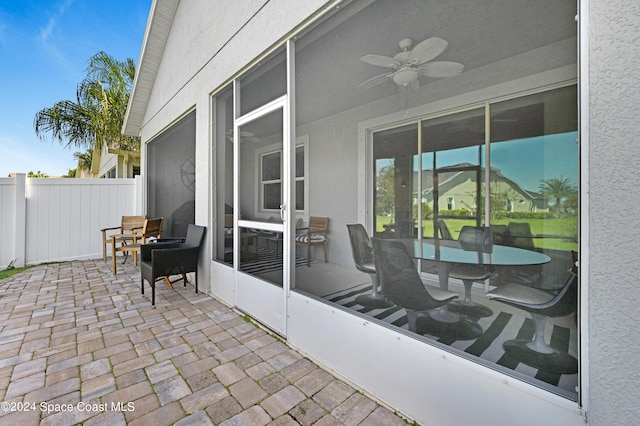 view of patio featuring a sunroom, fence, and a ceiling fan