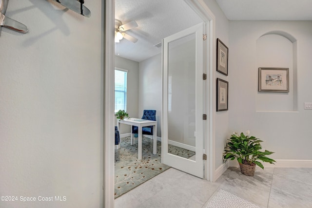 hall with a textured ceiling, visible vents, and baseboards