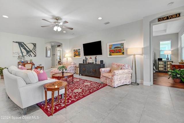 tiled living area featuring baseboards, arched walkways, ceiling fan, and recessed lighting