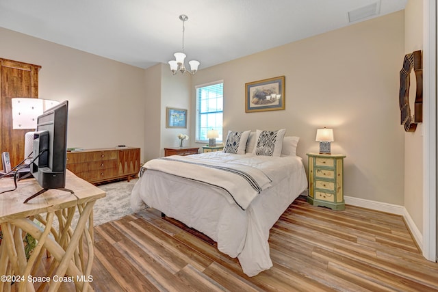 bedroom with light wood-type flooring, visible vents, baseboards, and an inviting chandelier