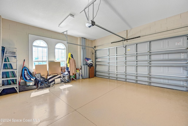 garage with a garage door opener and concrete block wall