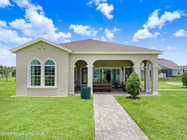 back of property with a yard, a porch, roof with shingles, and stucco siding