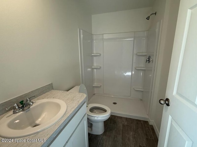 bathroom with wood-type flooring, toilet, vanity, and a shower