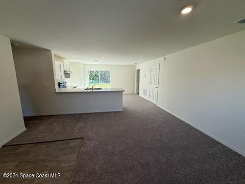 unfurnished living room with dark colored carpet