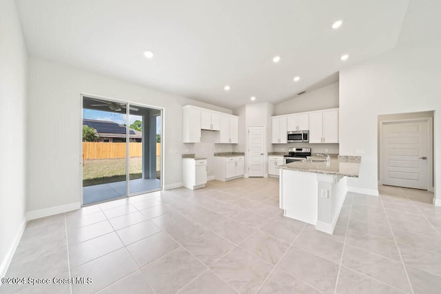 kitchen with kitchen peninsula, light stone countertops, stainless steel appliances, sink, and white cabinets