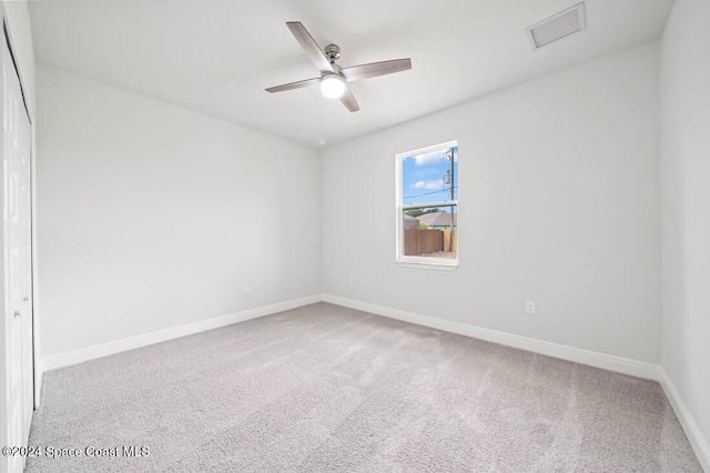 empty room featuring ceiling fan and light carpet