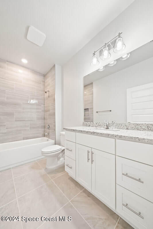 full bathroom with tile patterned floors, vanity, toilet, and tiled shower / bath combo