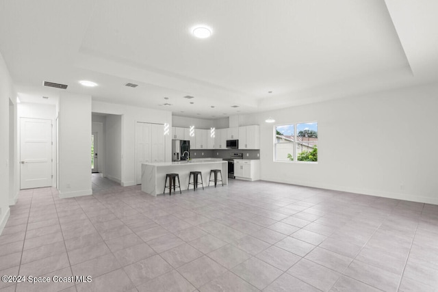 unfurnished living room with a raised ceiling and light tile patterned floors