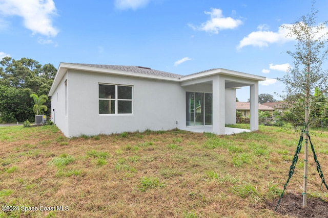 rear view of property with a yard and central AC