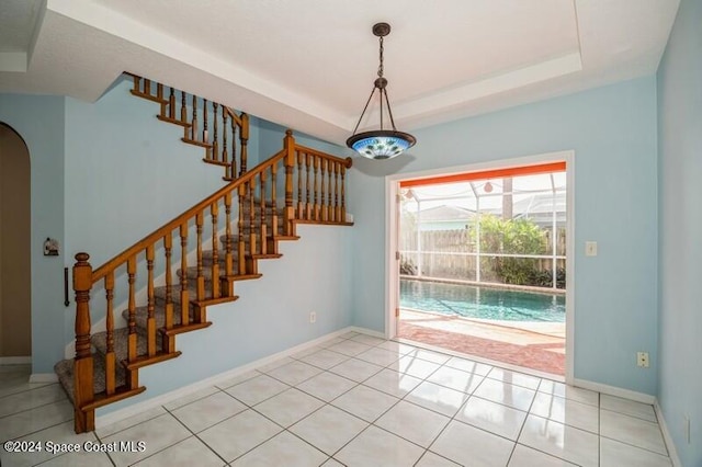 entryway with light tile patterned flooring and a raised ceiling