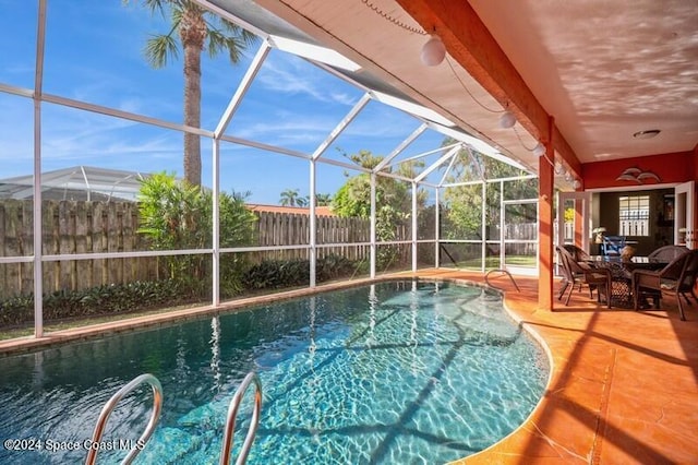 view of pool with ceiling fan, glass enclosure, and a patio area